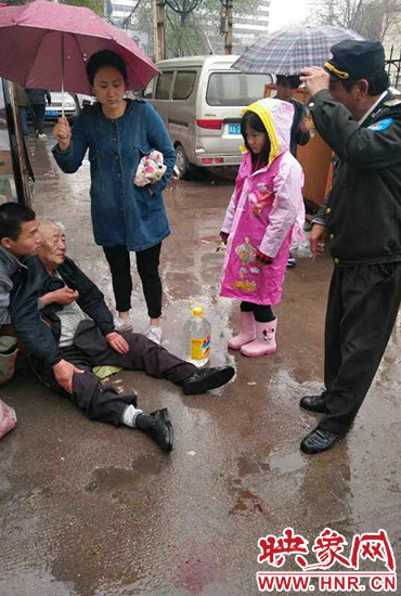 女孩為倒地老人撐傘。