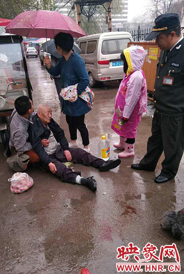 女孩為倒地老人撐傘。