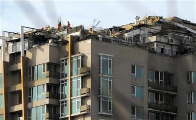 　　昨日，身穿橘黃色馬甲的工作人員在人濟(jì)山莊樓頂拆除違章建筑。新京報記者 吳江 攝