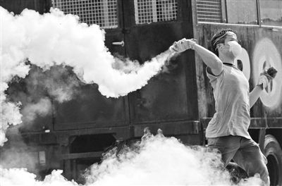 12月2日，泰國曼谷，一名反政府示威者在總理府附近向負(fù)責(zé)執(zhí)勤的警察投擲催淚彈。英拉請求示威者不要再試圖占領(lǐng)政府工作部門，不要逼迫政府工作人員選邊站。