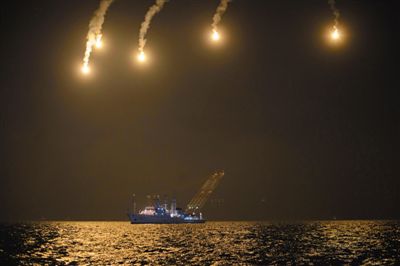 22日，搜救人員在照明彈的光亮下連夜搜救。