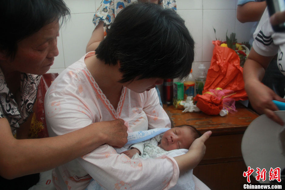 圖為久別重逢，獲救嬰兒母親悉心撫摸愛子。張一辰 攝