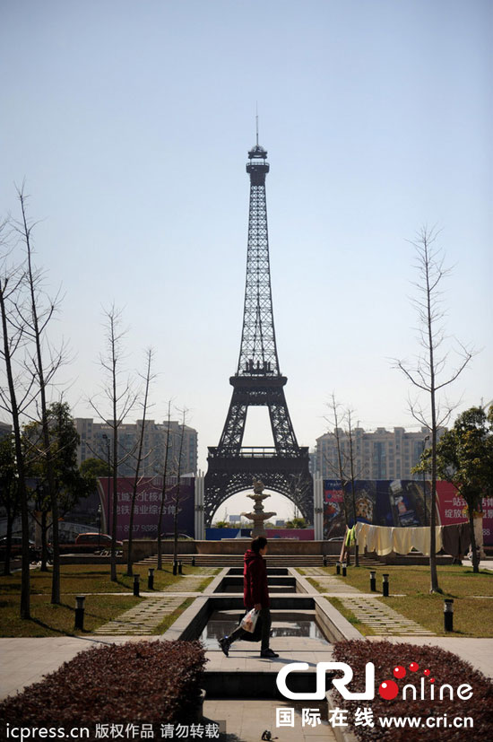 　2014年3月21日，杭州天都城，農(nóng)民在山寨埃菲爾鐵塔下耕作。圖片來源：東方IC