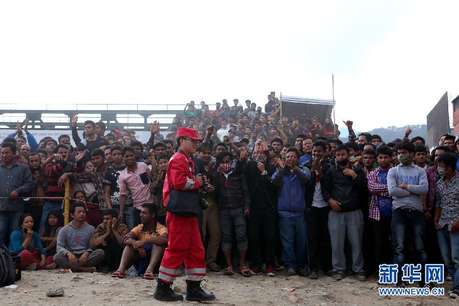 圍觀的尼泊爾民眾在中國國際救援隊成功搜救出幸存者后向搜救隊員歡呼致意。