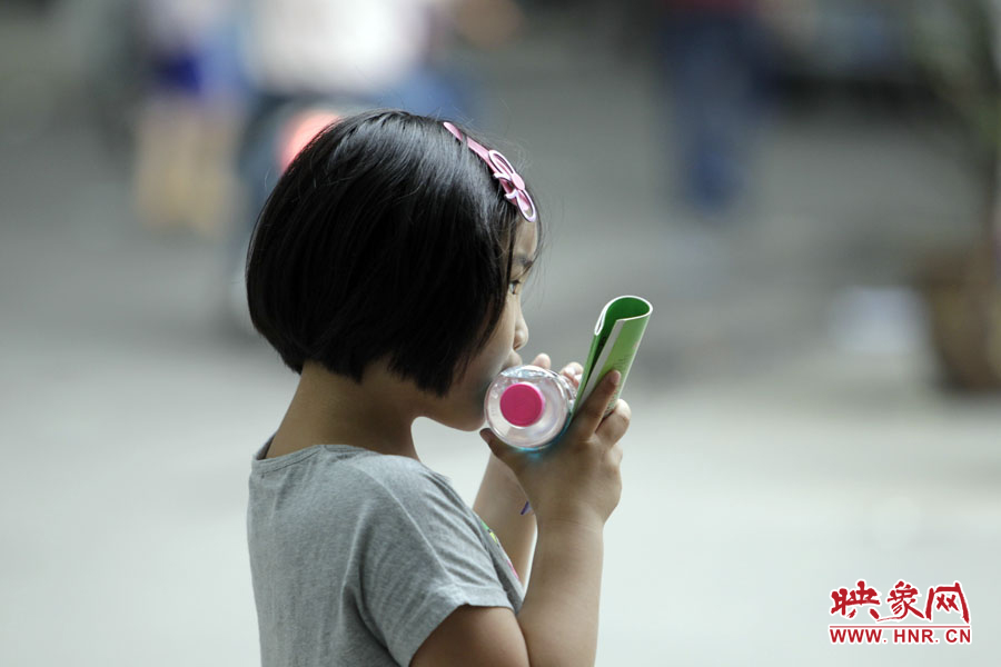 6月7日，鄭州回中考點，一名孩子拿著一瓶礦泉水，等待哥哥走出考場