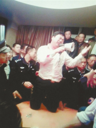 　4月19日，泰州市濱江工業(yè)園區(qū)管委會招待中心，一男子跪在酒桌上喊話求饒。李根 攝