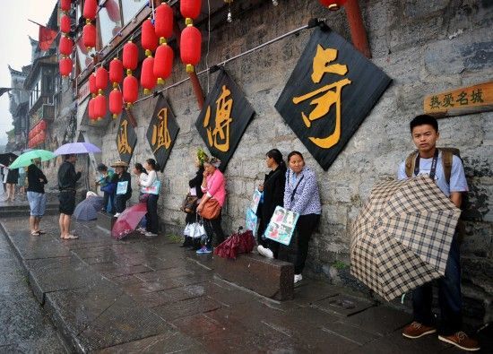 　4月29日上午11時20分，一些游客和古城當(dāng)?shù)氐木用穸阍谝粋€酒吧的屋檐下避雨。這些當(dāng)?shù)鼐用褚詾橛慰团恼罩\生，一場降雨讓他們的生意更加清淡。