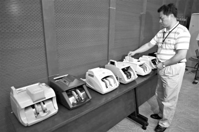 昨日，央行工作人員用各種驗鈔機對C1F9假幣進行測試，機器均能及時作出異常報警反應(yīng)。新京報記者 浦