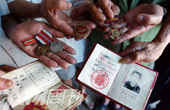 幾位志愿軍老兵展示自己的立功證、傷殘軍人證與勛章