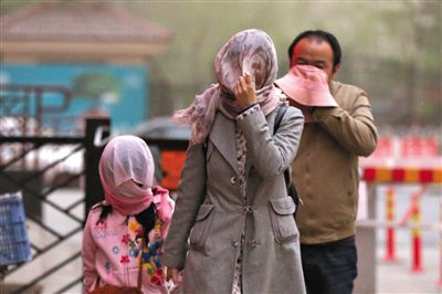 昨日下午，朝陽區(qū)豆各莊，行人將紗巾裹在頭上防沙塵。