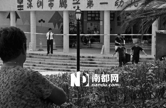 →7月19日，鵬興花園第一幼兒園門前，民警在現(xiàn)場進行完勘查取證后，園長和保安的尸體被運走。南都記者 徐文閣 攝