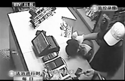 戴帽男子一手掐住加油站營業(yè)員，一手持發(fā)令槍指向另一營業(yè)員，要求“把錢給我裝起來”。