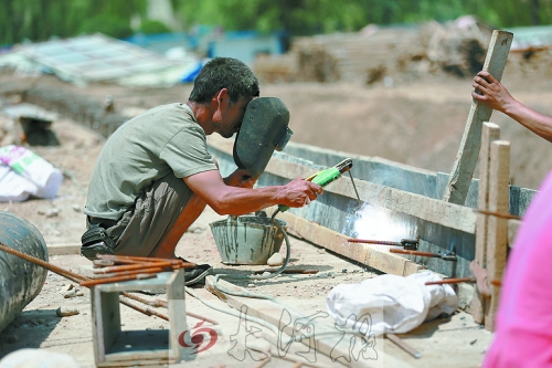 　正午陽光下，工地上的焊接工人還在認真工作。