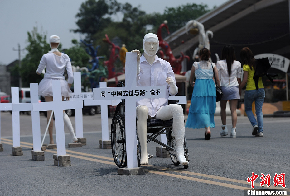 4月16日，重慶市洋人街上擺放著兩個(gè)受了傷的塑料人像“模特”，旁邊十字架上寫著向“中國式過馬路”說不