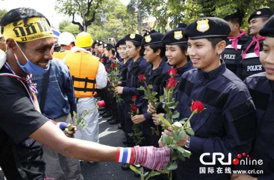 2013年12月03日,曼谷總理府與曼谷警署允許反政府示威民眾進(jìn)入,雙方進(jìn)入暫時(shí)“停戰(zhàn)”狀態(tài)迎接泰王生日。曼谷警察總署,女警們手持鮮花送給反政府示威民眾。圖片來源:Manish Swarup/東方IC