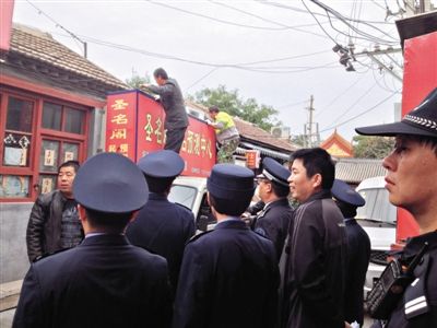 昨日下午,東城區(qū)工商、城管、公安等部門,對雍和宮附近的預(yù)測中心進(jìn)行清理整頓,站在車頂?shù)膬擅と苏鸪患摇邦A(yù)測中心”的招牌。因雍和宮、白云觀等文化景點外聚集大量算命先生,被媒體稱為“算命一條街”。本版攝影/新京報記者 李寧 攝