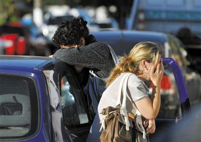 27日，遇難者親友在火災(zāi)現(xiàn)場(chǎng)旁哭泣。