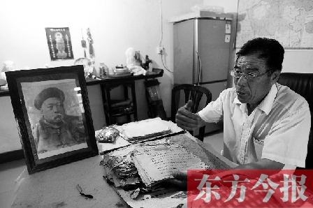 　魏樹紹手拿《物權法講義》手稿，在講訴先祖書寫“物權法”的歷史（相框里就是魏聯(lián)奎）