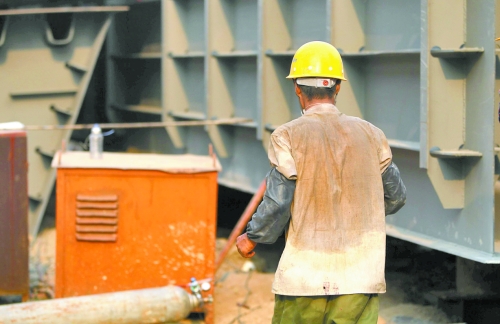 工地上，一建筑工人的衣服被汗水浸透。