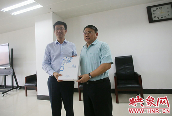 阿里云計算總裁胡曉明向河南省新聞出版廣電局局長朱夏炎遞交《中原云平臺交付手冊》。