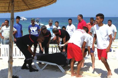 6月26日，在突尼斯蘇塞，救生員和醫(yī)務(wù)人員在發(fā)生襲擊事件的海灘運送一名死者的遺體。新華社發(fā)