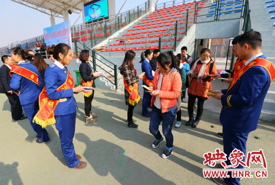 活動(dòng)現(xiàn)場工作人員給同學(xué)們發(fā)放宣傳冊、環(huán)保袋。