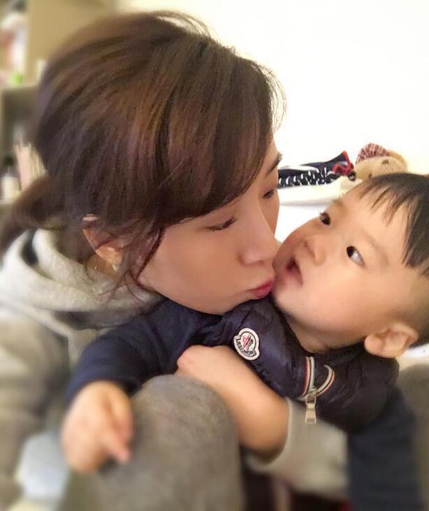 照片中李念狂吻兒子，小寶貝自顧自地玩著。