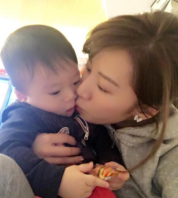 照片中李念狂吻兒子，小寶貝自顧自地玩著。