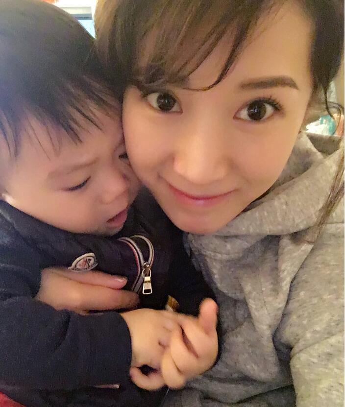 照片中李念狂吻兒子，小寶貝自顧自地玩著。