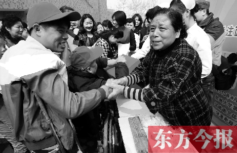 昨日，鄭大四附院的大樓前，“面人鄭”鄭玉芬（右）向前來捐款的殘疾人表示感謝