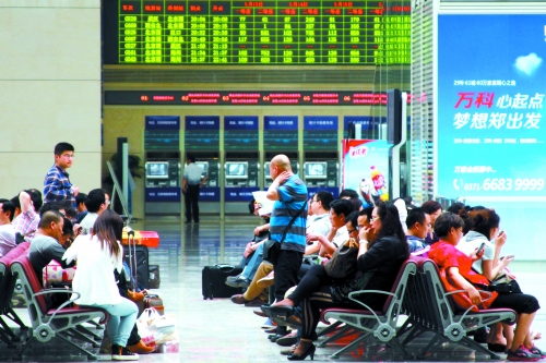 候車大廳溫度很高，一名乘客一手扇風(fēng)、一手擦汗