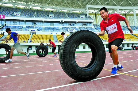 8月15日，運(yùn)動員們正在進(jìn)行推輪胎賽跑。