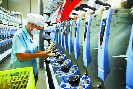7月3日，在鄧州市永泰棉紡有限公司電腦控制全自動紡紗車間，紡織工人正在生產棉紗。