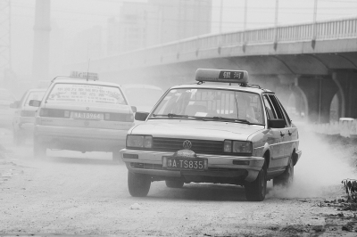 施工的道路上，車輛通過(guò)塵土飛揚(yáng)。