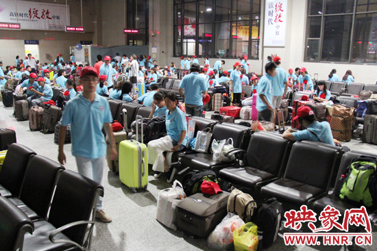 大學(xué)生志愿者在火車(chē)站候車(chē)室內(nèi)整裝待發(fā)。