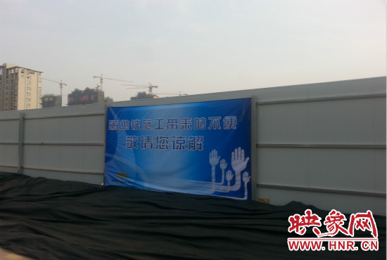 道路南側(cè)圍起了白色的圍擋，墻上標(biāo)示著“因地鐵施工帶來的不便敬請(qǐng)您諒解”的提示牌。