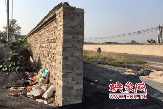 一墻之隔，一邊是道路，一邊是垃圾和荒草，市民質(zhì)疑其為遮羞墻。
