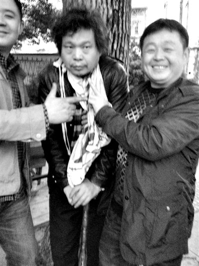 兩名接訪人員與患有癌癥的訪民段新德合影時，面帶笑容擺出勝利的手勢。