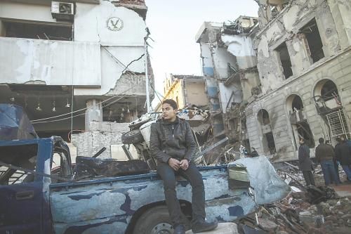 埃及曼蘇拉市警察局24日遭汽車炸彈襲擊，被疑是穆兄會(huì)的報(bào)復(fù)。圖為一名男子在被炸毀的警察局前。