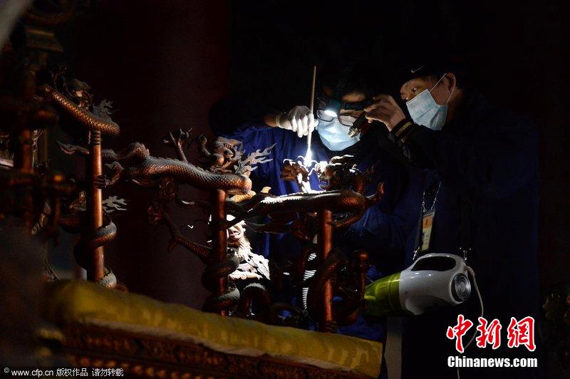 圖為工作人員使用軟毛刷和吸塵器對太和殿的金漆雕龍寶座除塵。