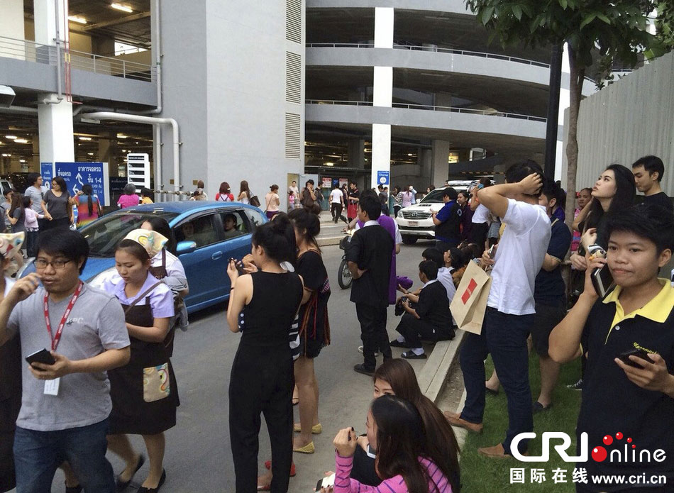 當(dāng)?shù)貢r間2014年5月5日，泰國清萊，工人們站在一棟大樓外避難。