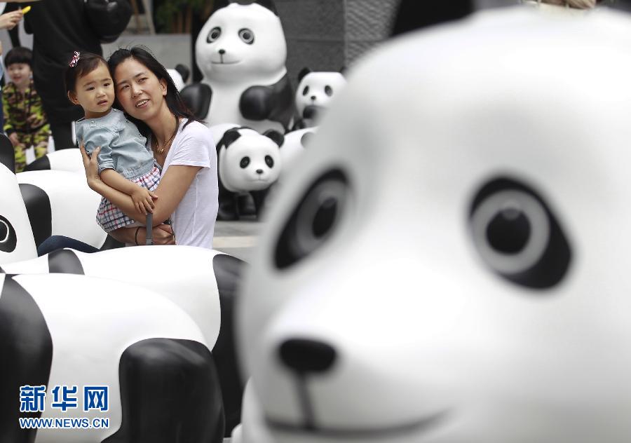 6月2日，一位家長(zhǎng)帶著孩子在上海街頭和大熊貓模型合影。