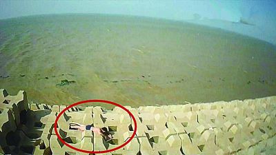 孫正龍游上岸，趴在海邊精疲力盡。