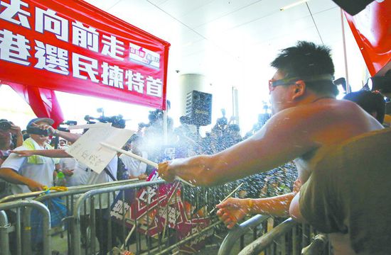 17日，在香港立法會(huì)外，一名反對(duì)政改的男子向支持派人群投擲標(biāo)牌。