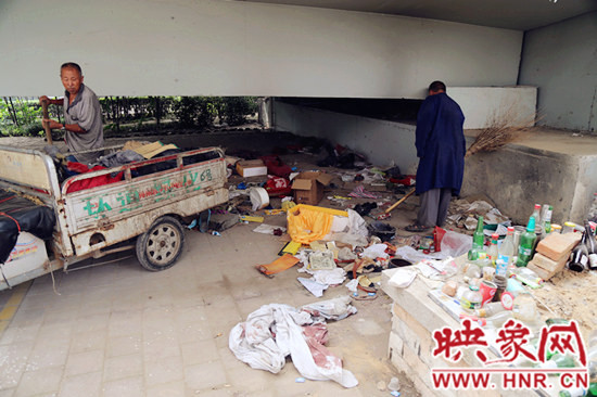 負(fù)責(zé)高架橋下綠化的人員在清理流浪漢留下的垃圾和雜物。