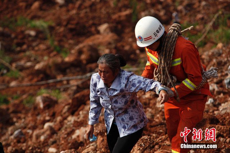 一位消防戰(zhàn)士將一位失去親人的老人扶離滑坡點。