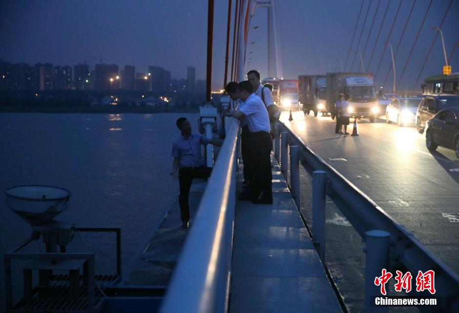 圖為武漢警方談判專家正在與翻爬至大橋外側(cè)護欄的劫持者談判。