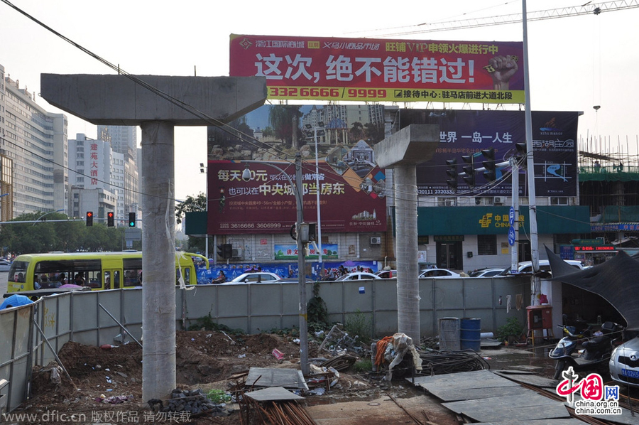 過街天橋一側(cè)的橋樁早已打好,可是對(duì)面的郵政銀行網(wǎng)點(diǎn)依舊在照常營(yíng)業(yè)。