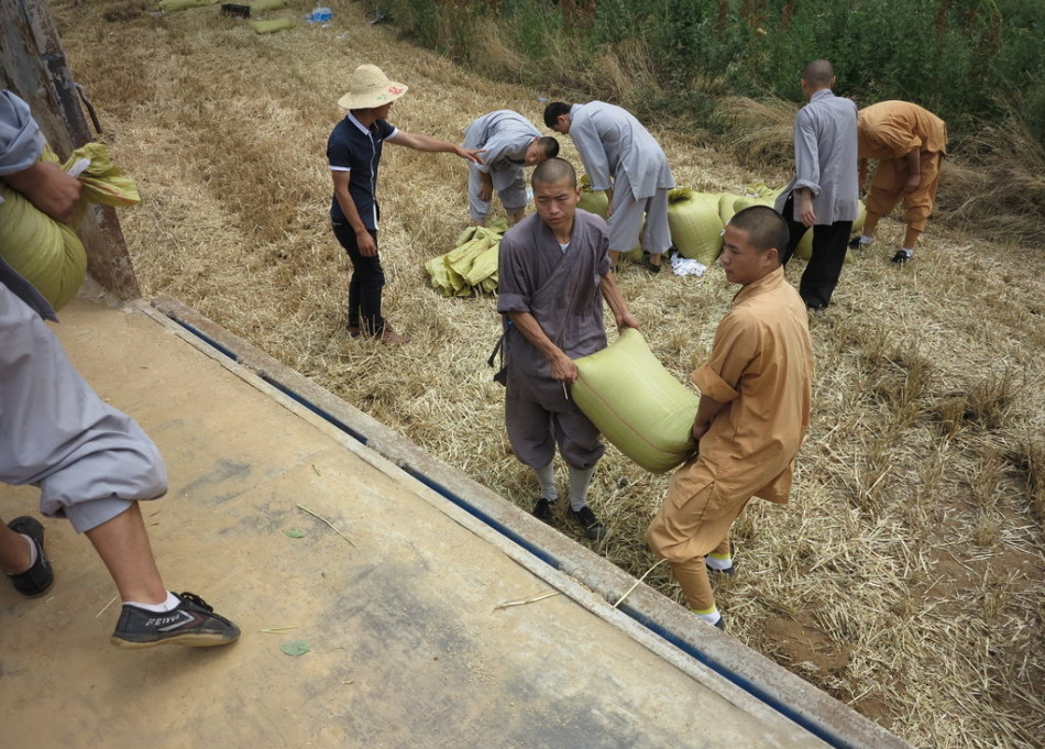 武僧將打包后的糧食集中至運輸車輛上。