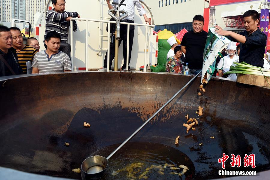 工作人員向大鍋內(nèi)加入油和姜等烹飪調(diào)料。 圖片來源：CFP視覺中國